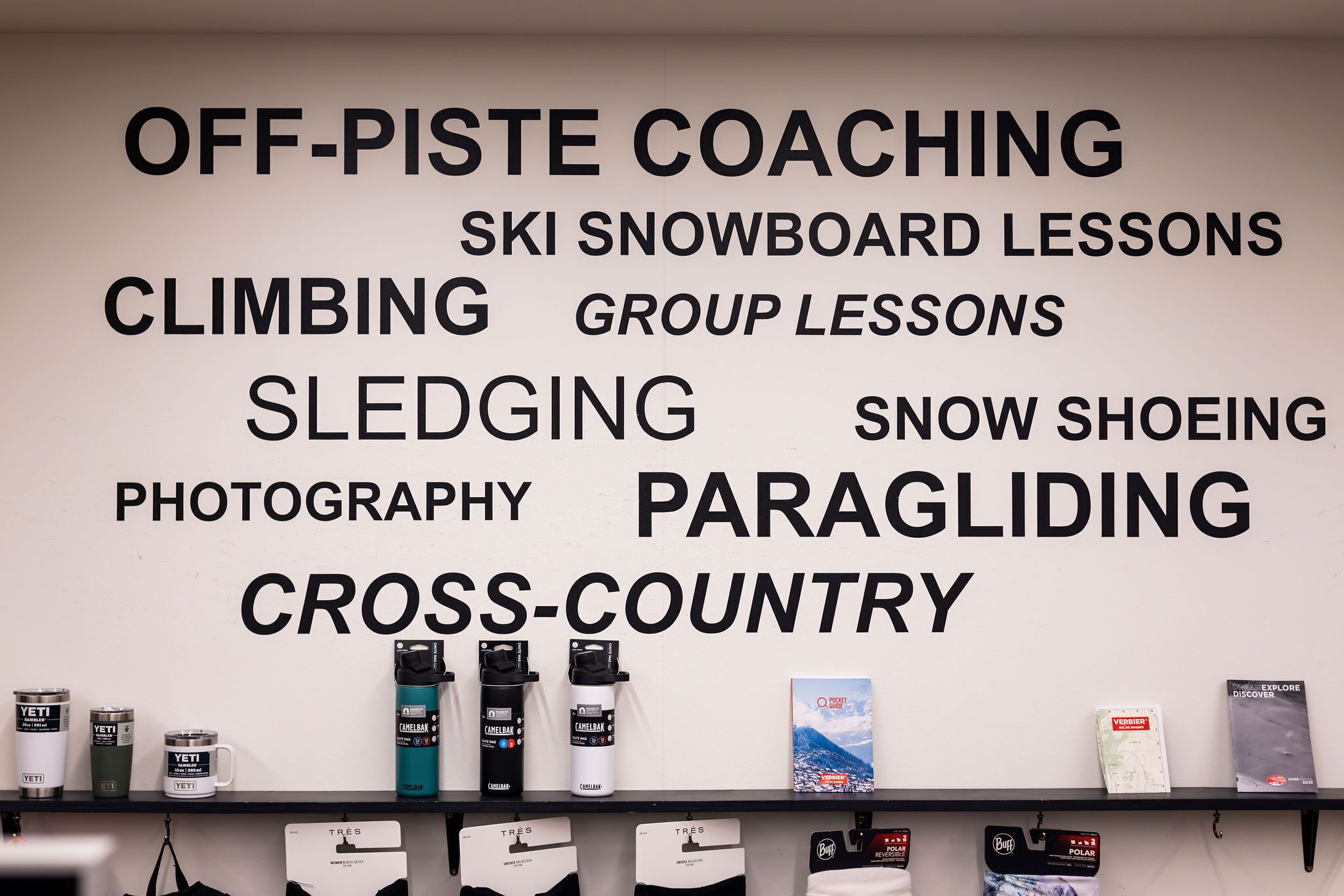 A wall with various outdoor activities listed such as off-piste coaching, ski snowboarding lessons, climbing, group lessons, sledging, snowshoeing, photography, paragliding, and cross-country.