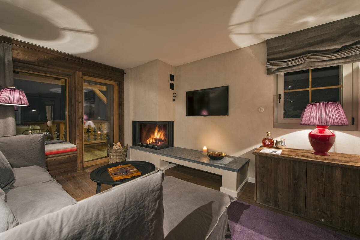 A modern living room with a fireplace, a sofa, a coffee table, and a TV mounted on the wall.