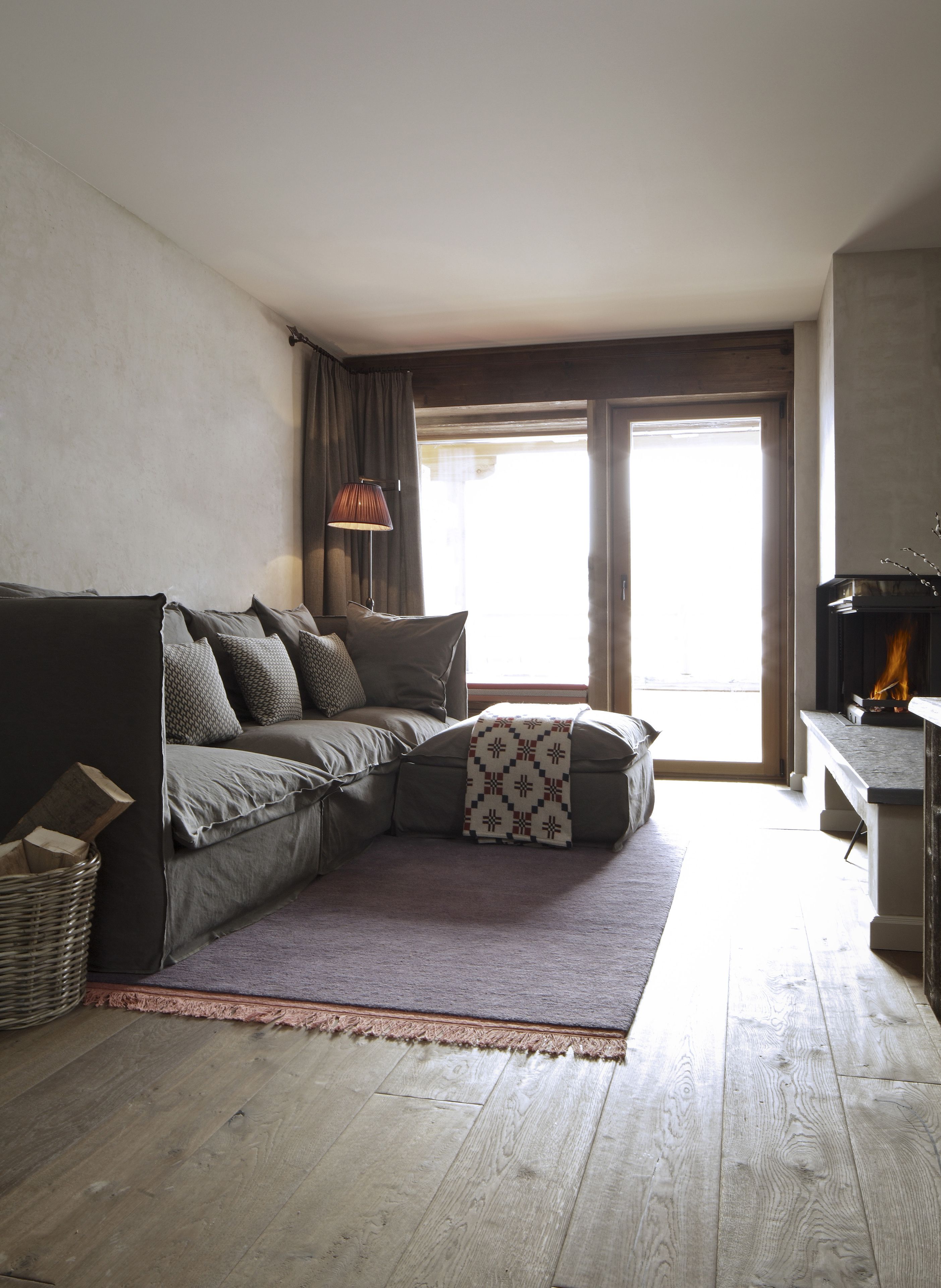 A living room with a sectional sofa, a patterned throw blanket, a floor lamp, and a fireplace.