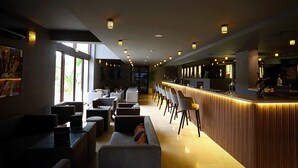 Un área de bar moderna con una barra larga, taburetes y distintos arreglos de asientos.