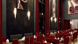 Un restaurante con sillas y mesas rojas, ventanas amplias y decoraci ón en las paredes.