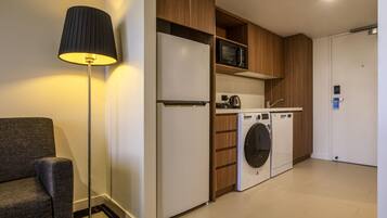 A compact kitchenette with a refrigerator, microwave, and washing machine.