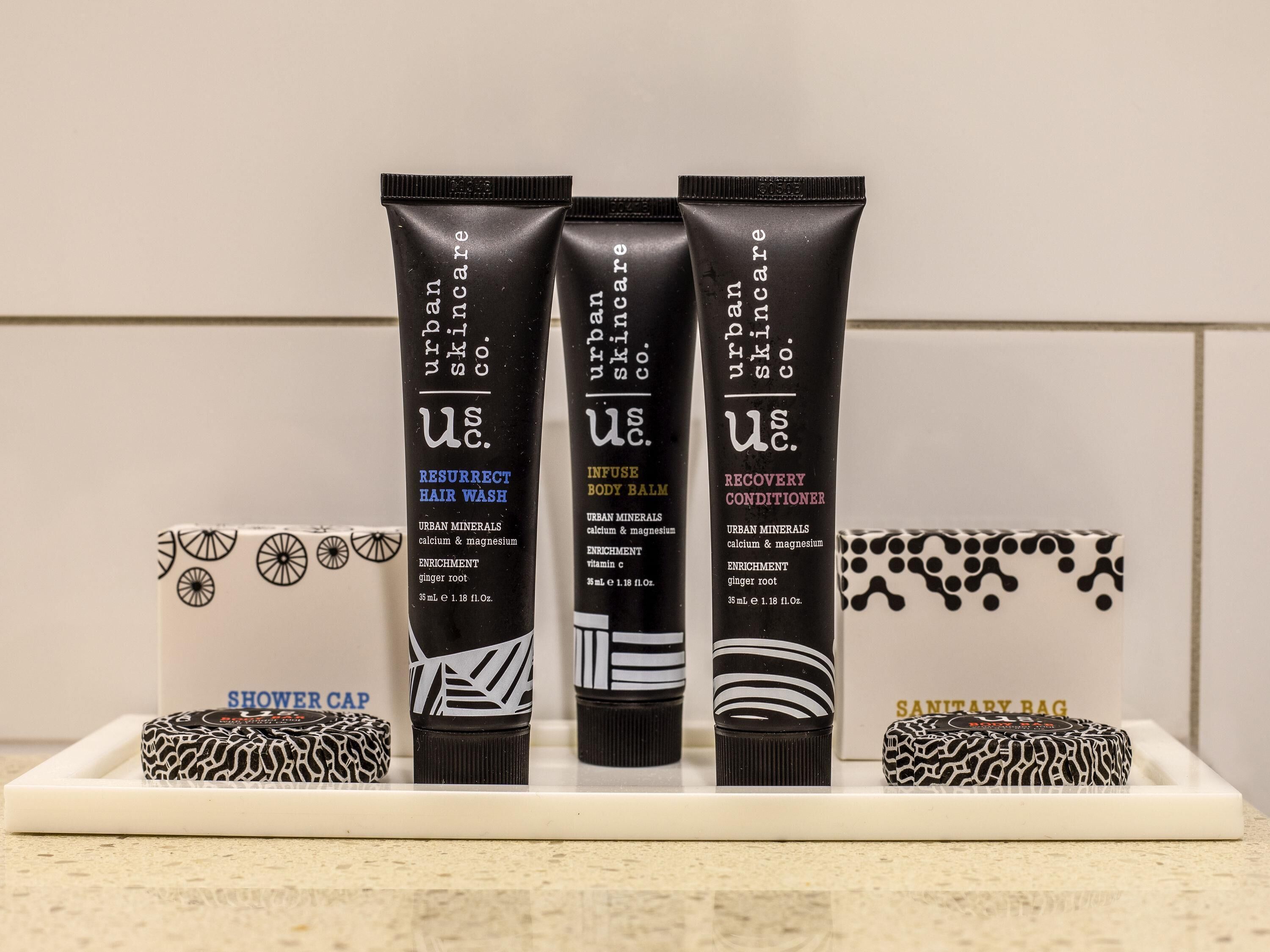 Trois produits de soins pour la peau sont présentés sur une étagère, accompagnés d'un bonnet de douche et d'un sac pour articles d'hygiène féminine.