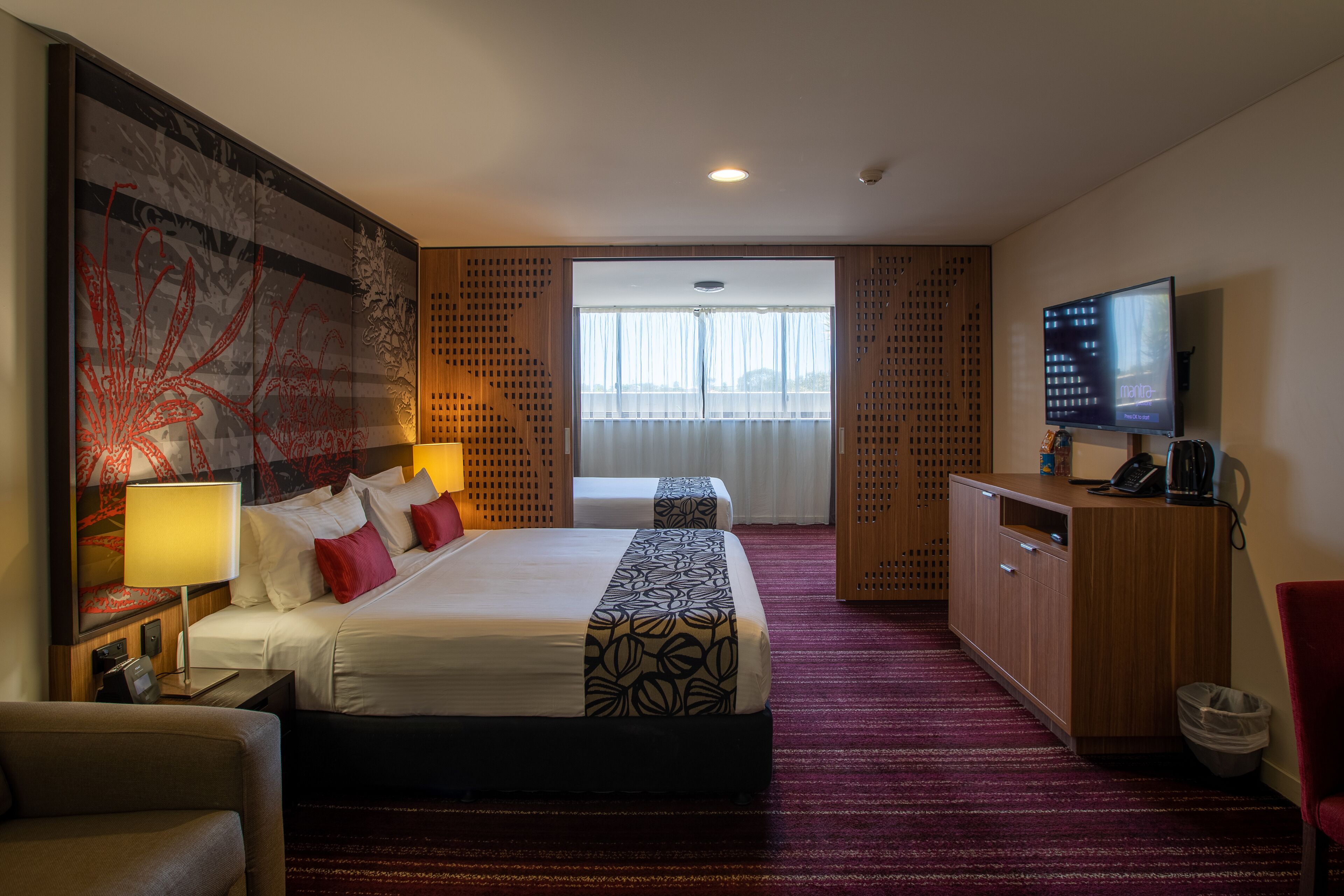 Een hotelkamer met een groot bed, een bureau, een televisie en uitzicht op de omgeving.
