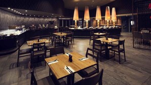 A restaurant with multiple tables and chairs, a bar area, and pendant lighting. - Mantra Gladstone (Barney Point)