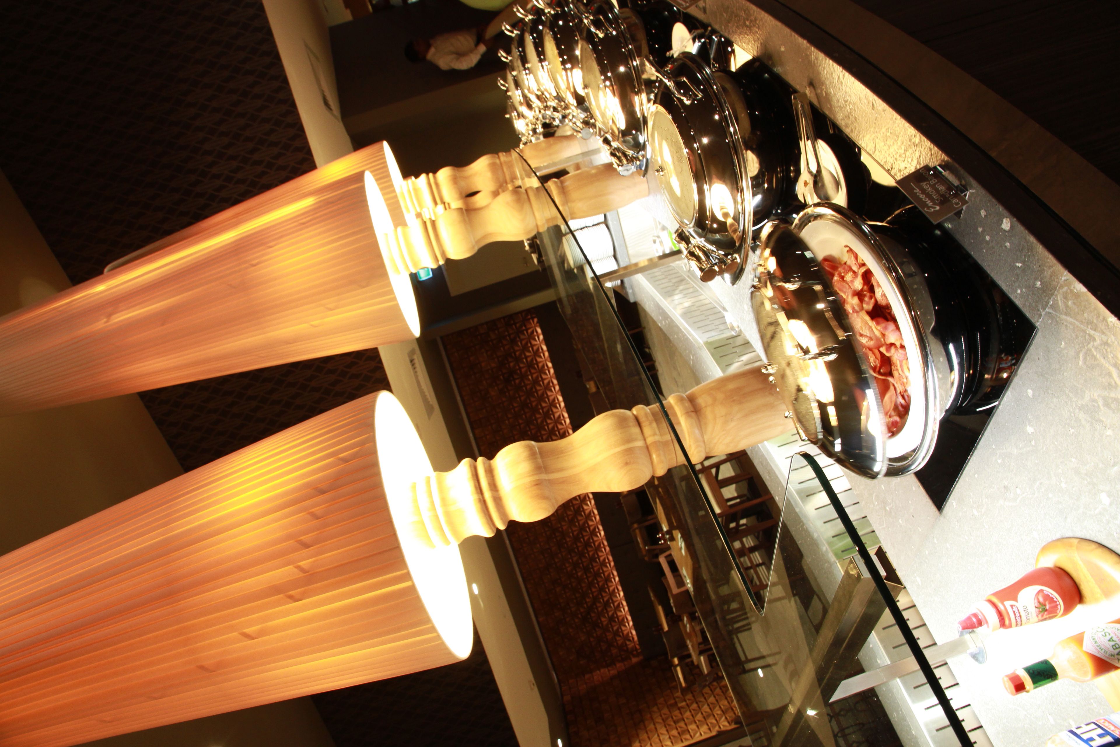 Un espace repas avec une longue table, un éclairage suspendu et divers objets disposés sur la table, notamment une bouteille et un bol.