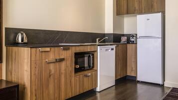 A modern kitchen with wooden cabinets, a built-in microwave, a dishwasher, and a white refrigerator.