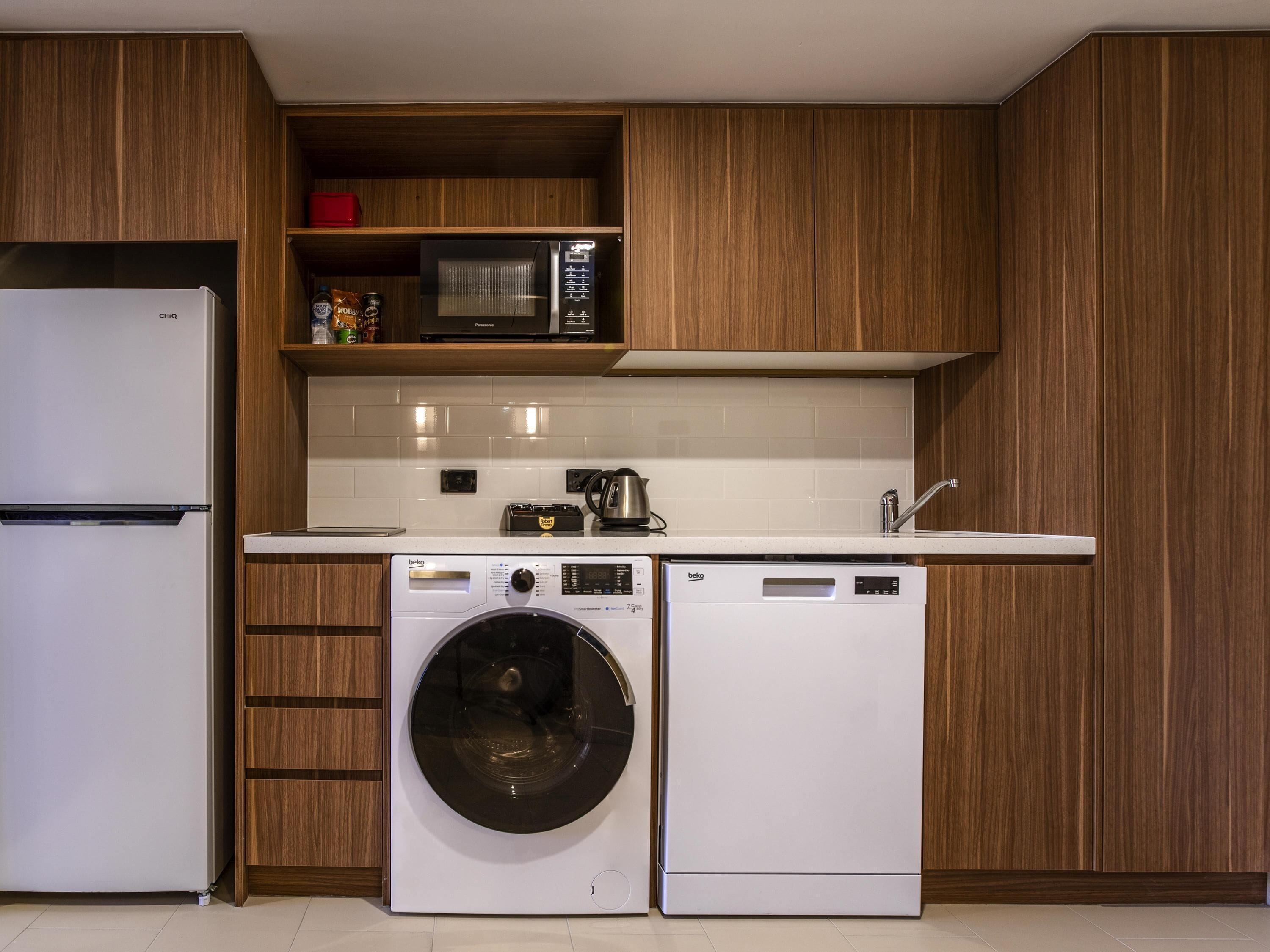 Una cocina compacta equipada con refrigerador, microondas, lavadora y cafetera.