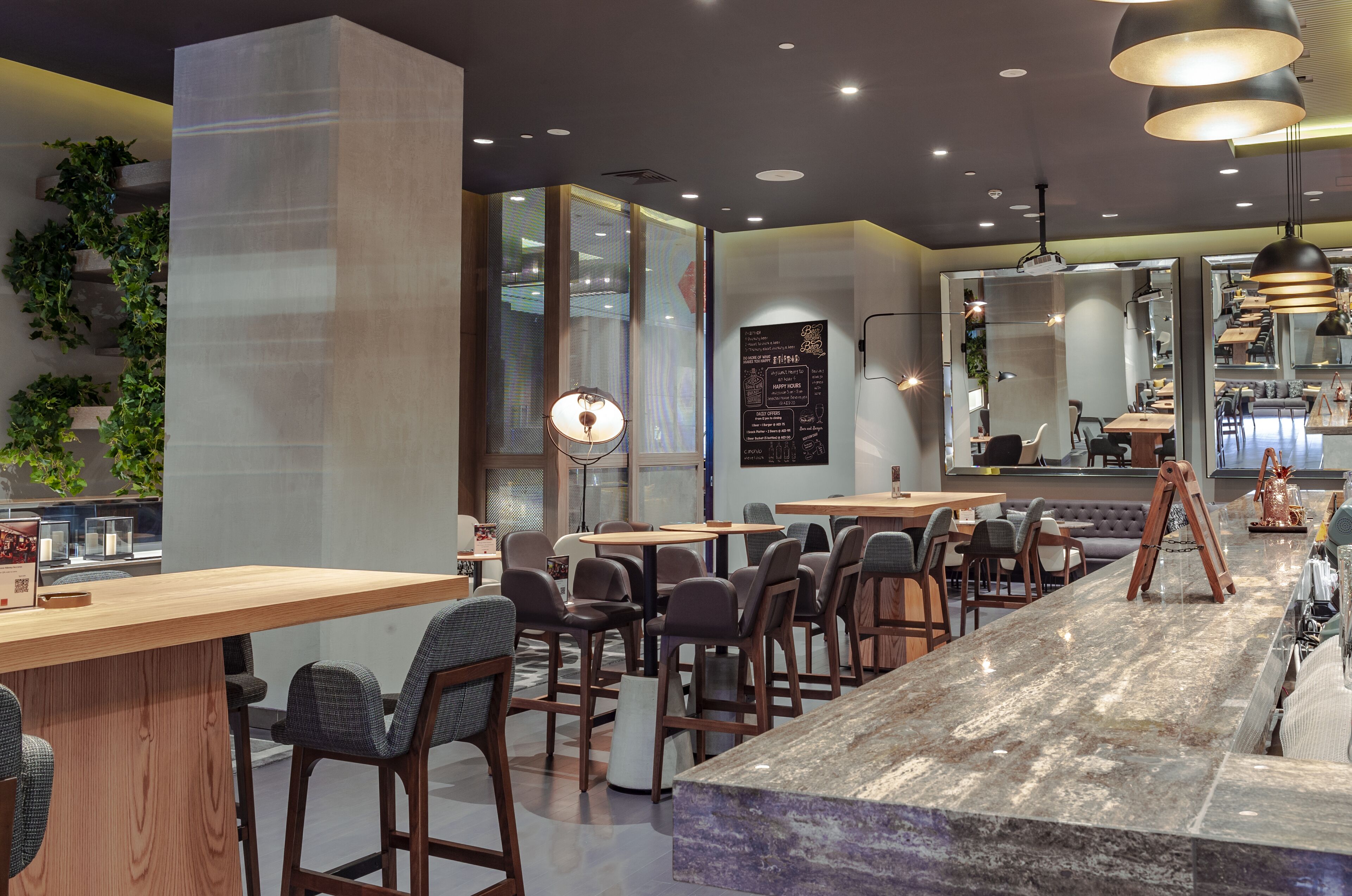 Un café moderne avec des tables et des chaises en bois, un comptoir en marbre et des luminaires suspendus.