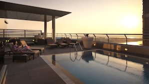 A rooftop pool area with lounge chairs and a view of the sunset. - Centro Capital Centre (Abu Dhabi)