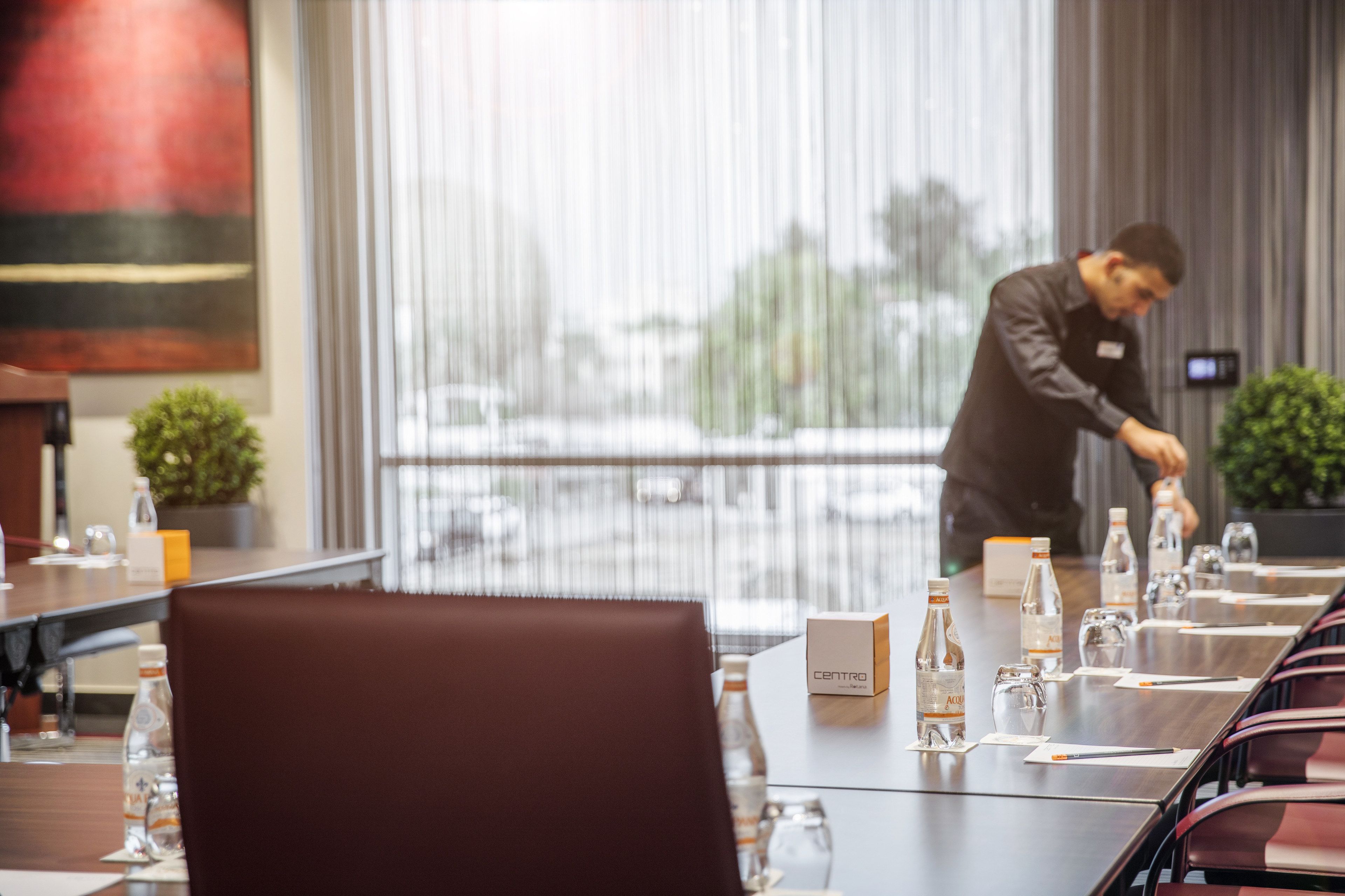 A conference room with a long table, chairs, water bottles, and a sign labeled "CENTRO".