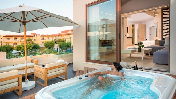 A modern living room with a large window, a sofa, and a coffee table. - Oscar Suites & Village (Chania)