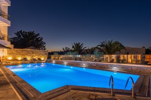 Een buitenzwembad, parasols bij het zwembad en ligstoelen