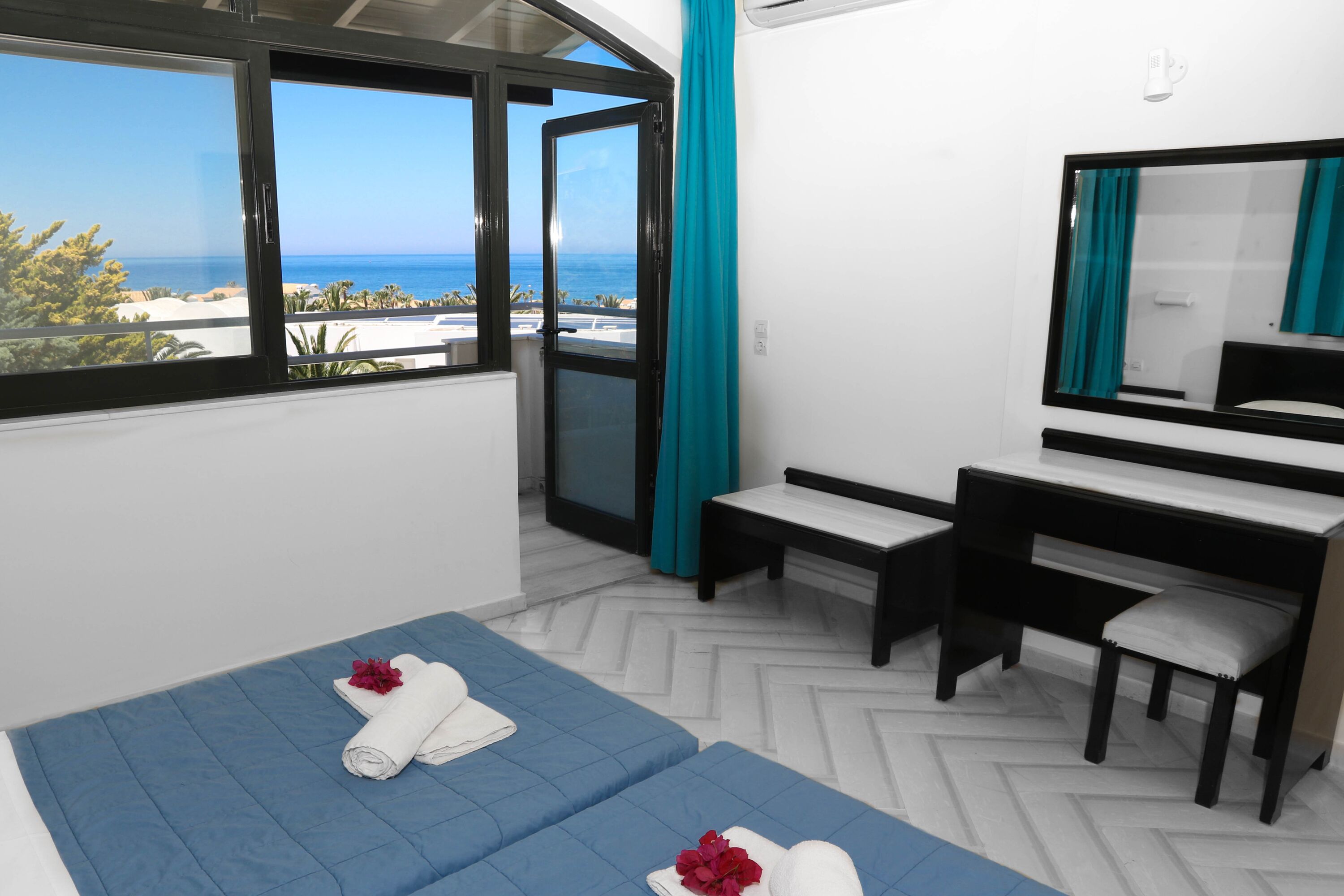 Una habitación de hotel con una cama, un escritorio y vista al océano.