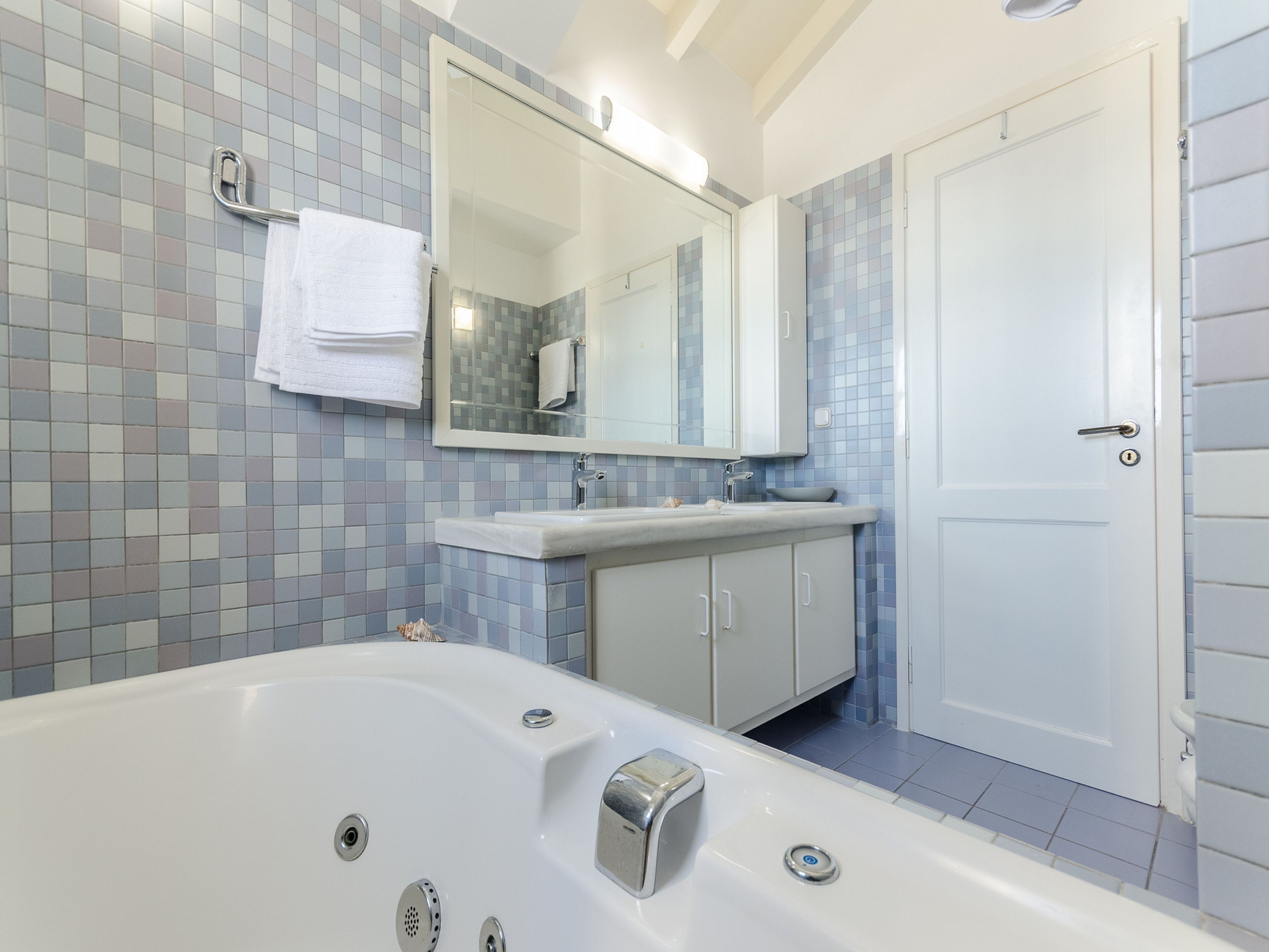 Un baño moderno con una bañera grande, un lavamanos y un espejo encima.