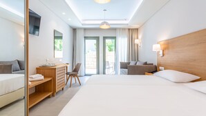 A modern hotel room with a large bed, a desk, a chair, and a sofa. - Anna Maria Village (Hersonissos)