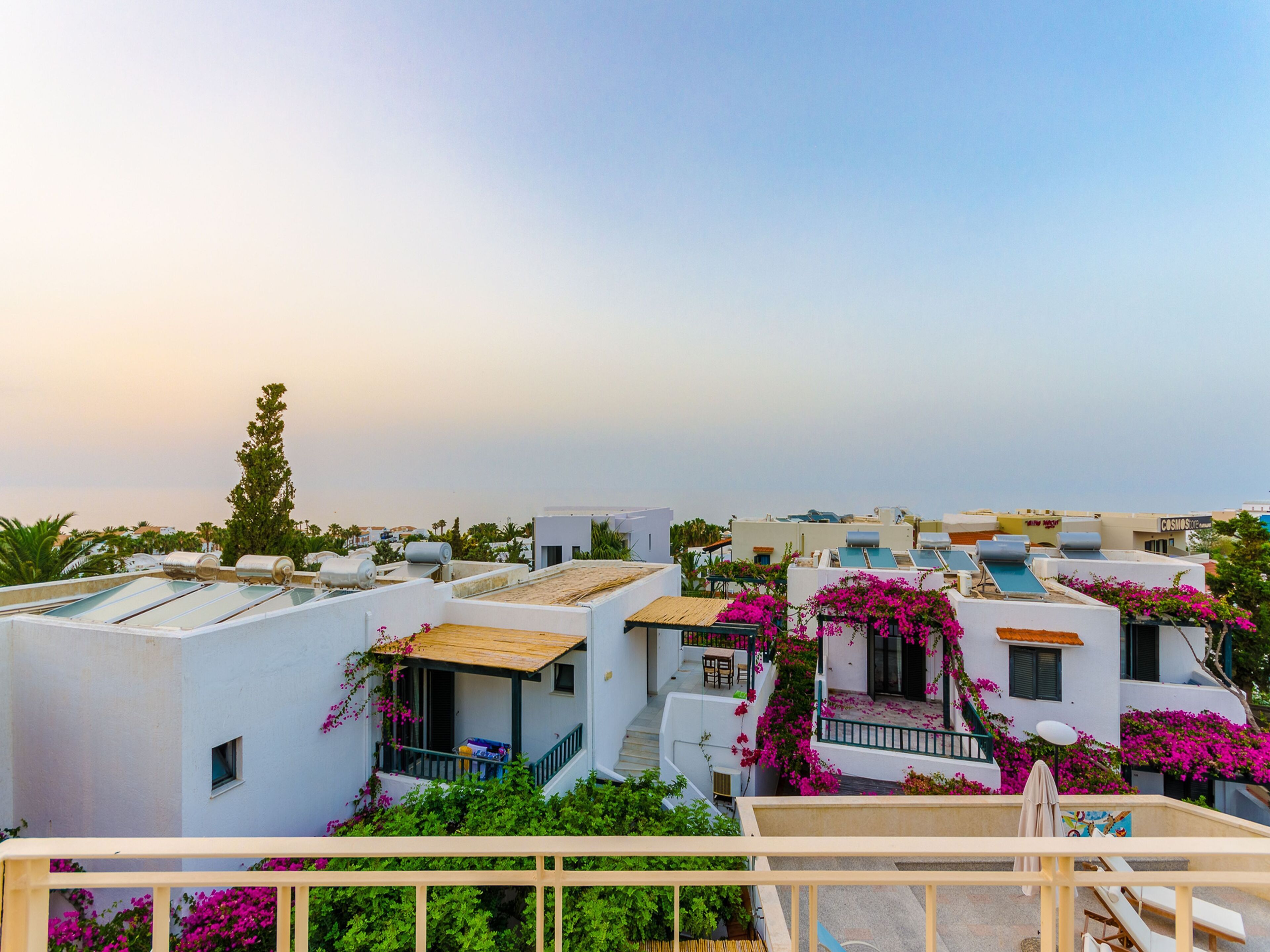 Zona residencial con edificios blancos, algunos con balcones, y una vista despejada al mar al fondo.