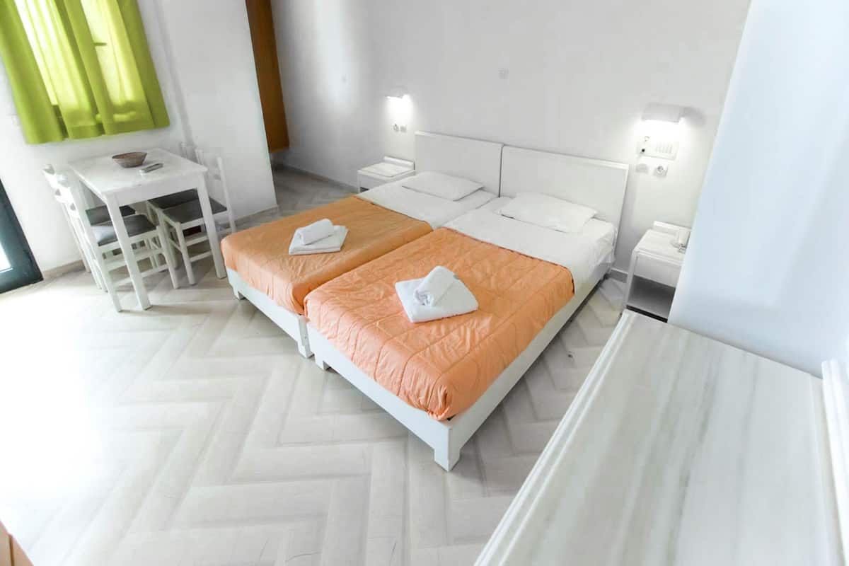 A hotel room with two beds, a desk, and a chair.