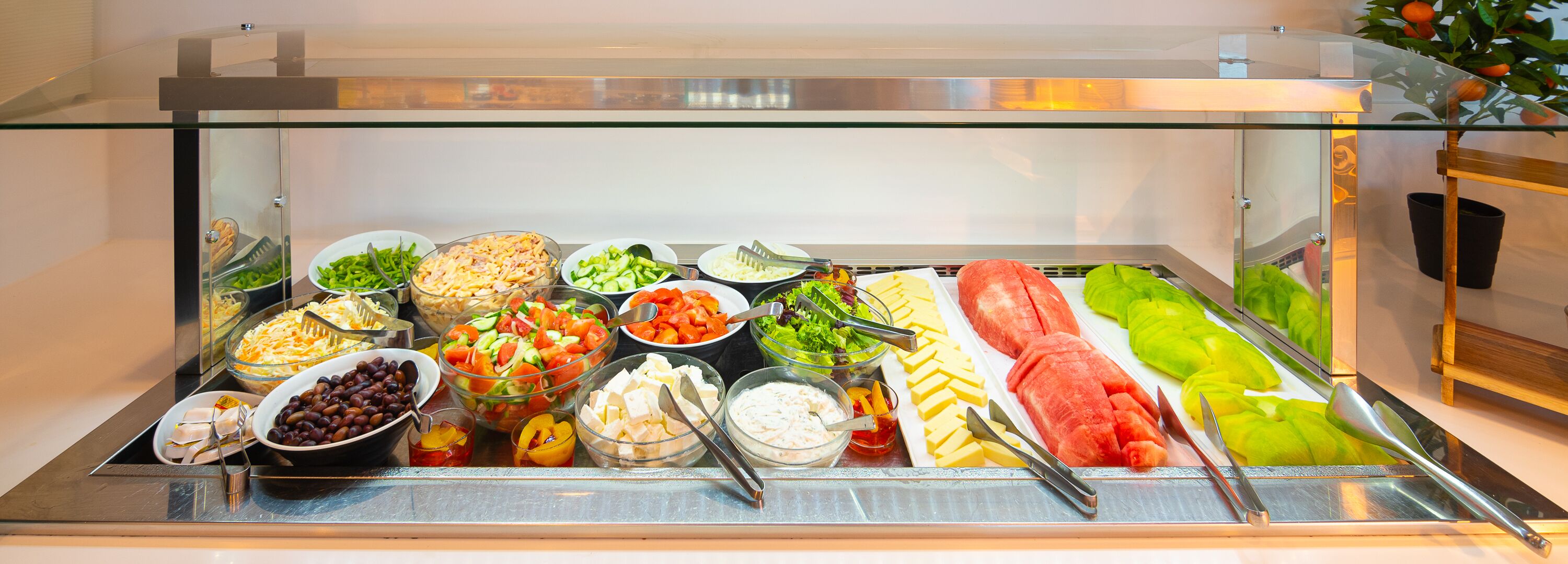 A buffet with various food items including salads, cheeses, and fruits.