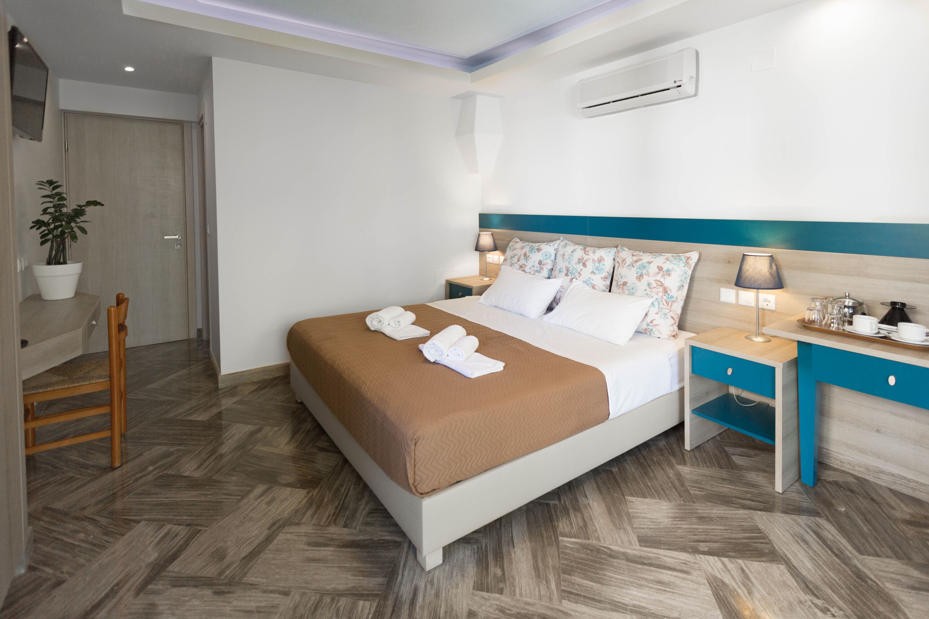 A neatly arranged hotel room with a bed, bedside tables, a chair, and a potted plant.