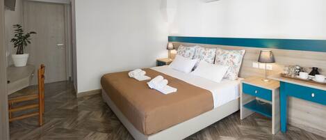 A neatly arranged hotel room with a bed, bedside tables, a chair, and a potted plant.