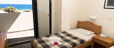Un dormitorio con cama, mesita de noche, ventana con vista al océano y una puerta.