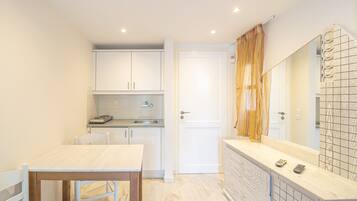Una cocina compacta con armarios blancos, una mesa de madera y un salpicadero azulejado.