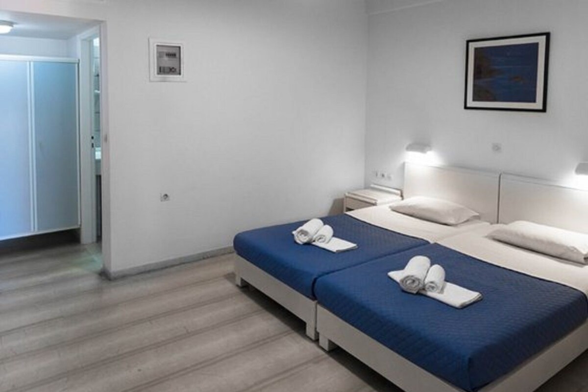 Habitación de hotel con dos camas, una mesita de noche y un cuadro en la pared.