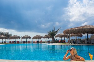 Una piscina al aire libre, sombrillas, sillones reclinables de piscina