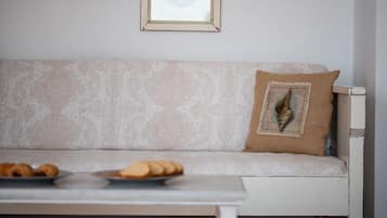A white sofa with a patterned cushion and a decorative pillow with a shell design.