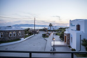 A coastal street with white buildings, a palm tree, and a sign for 'Plaza Beach'. - Plaza Beach Hotel (Naxos)