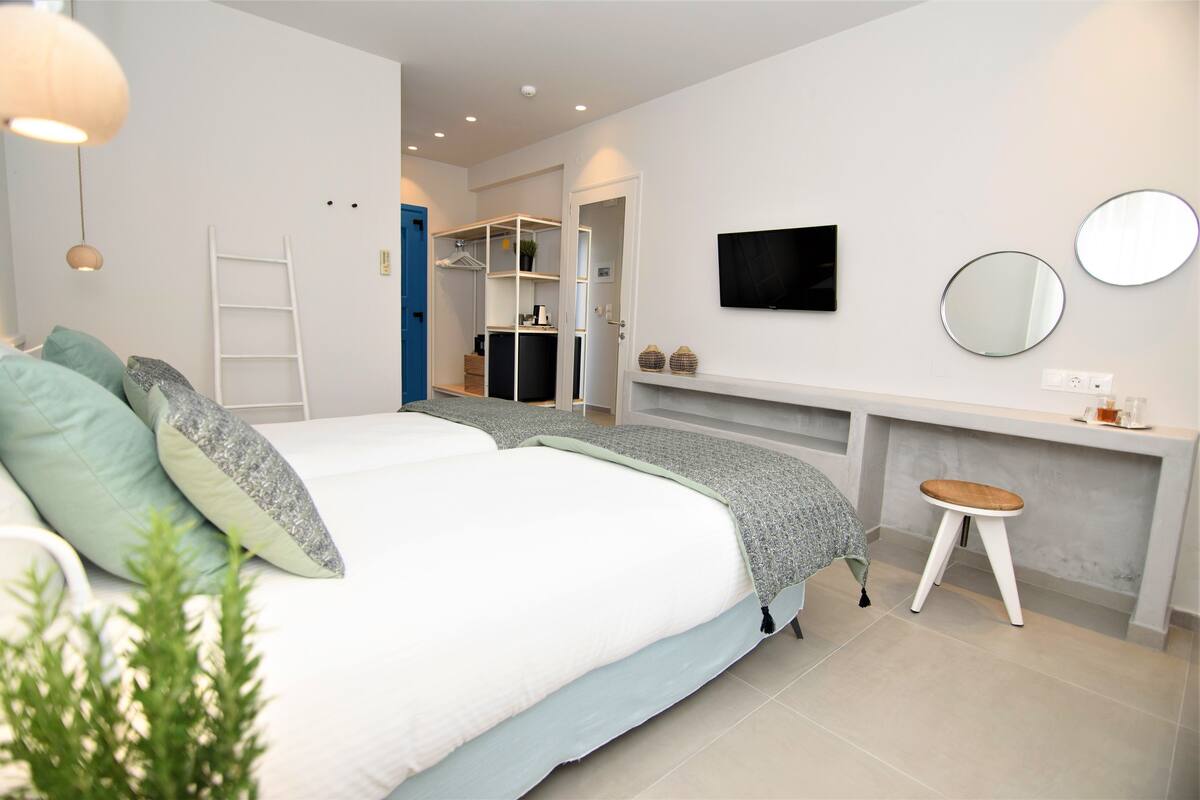 Ein Schlafzimmer mit Bett, Schreibtisch, Stuhl, Fernseher und Kleiderschrank.