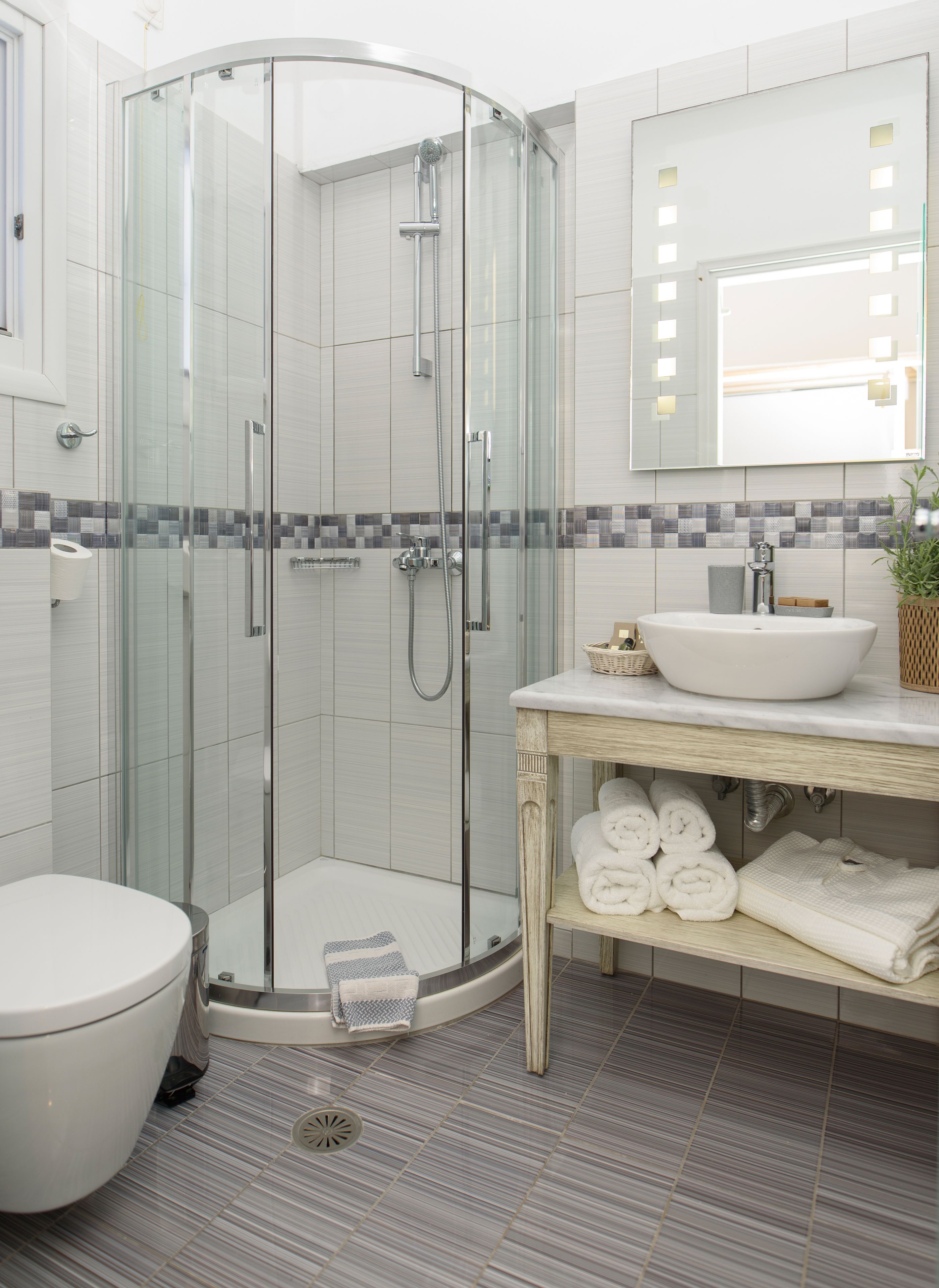 A modern bathroom with a glass-enclosed shower, a white sink, and a toilet.