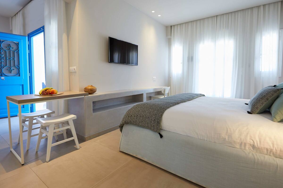 Ein modernes Schlafzimmer mit einem Bett, einem Schreibtisch und einem Fernseher.