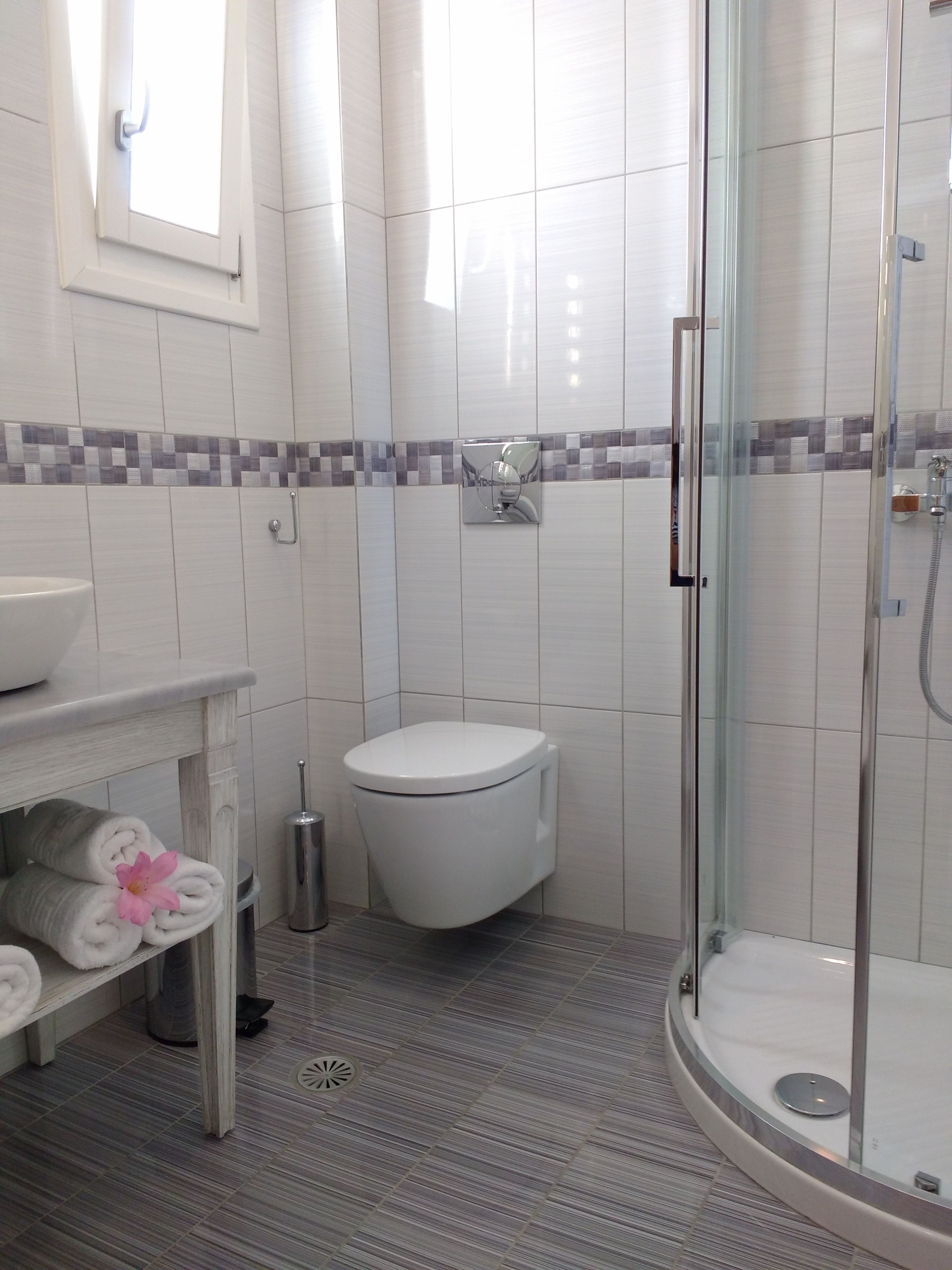 A modern bathroom with a glass-enclosed shower, a toilet, and a sink.