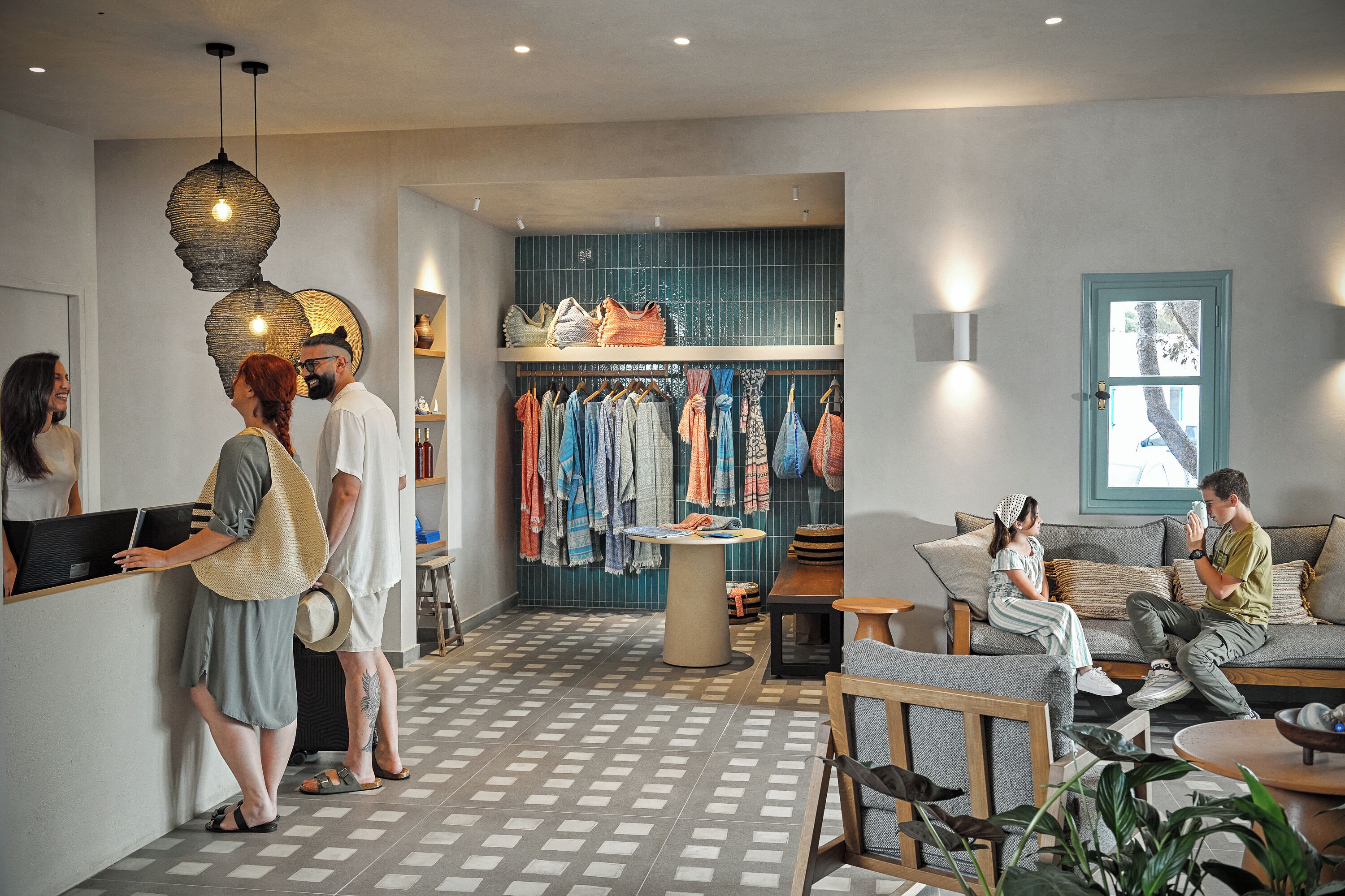 Un intérieur moderne avec un sol à carreaux, un coin salon comprenant un canapé et des fauteuils, ainsi qu’un portant à vêtements avec différents articles.