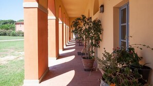 A covered corridor with arches, potted plants, and a window. - Hotel Casale la Sterpaia Pisa (San Giuliano Terme)