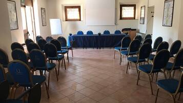 Un salón de conferencias con una larga mesa, sillas azules, una pizarra y cuadros en las paredes.