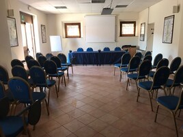 Un salón de conferencias con una larga mesa, sillas azules, una pizarra y cuadros en las paredes.