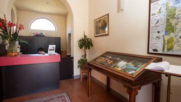 Un espace d’accueil comprenant un comptoir, une carte encadrée et une vitrine contenant des livres.