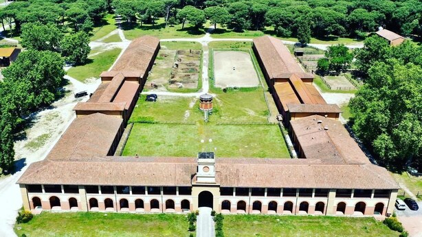 A large, rectangular building with a central courtyard, surrounded by trees and open spaces. - Hotel Casale la Sterpaia Pisa (San Giuliano Terme)
