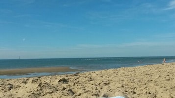Una playa arenosa con cielo despejado y mar tranquilo.