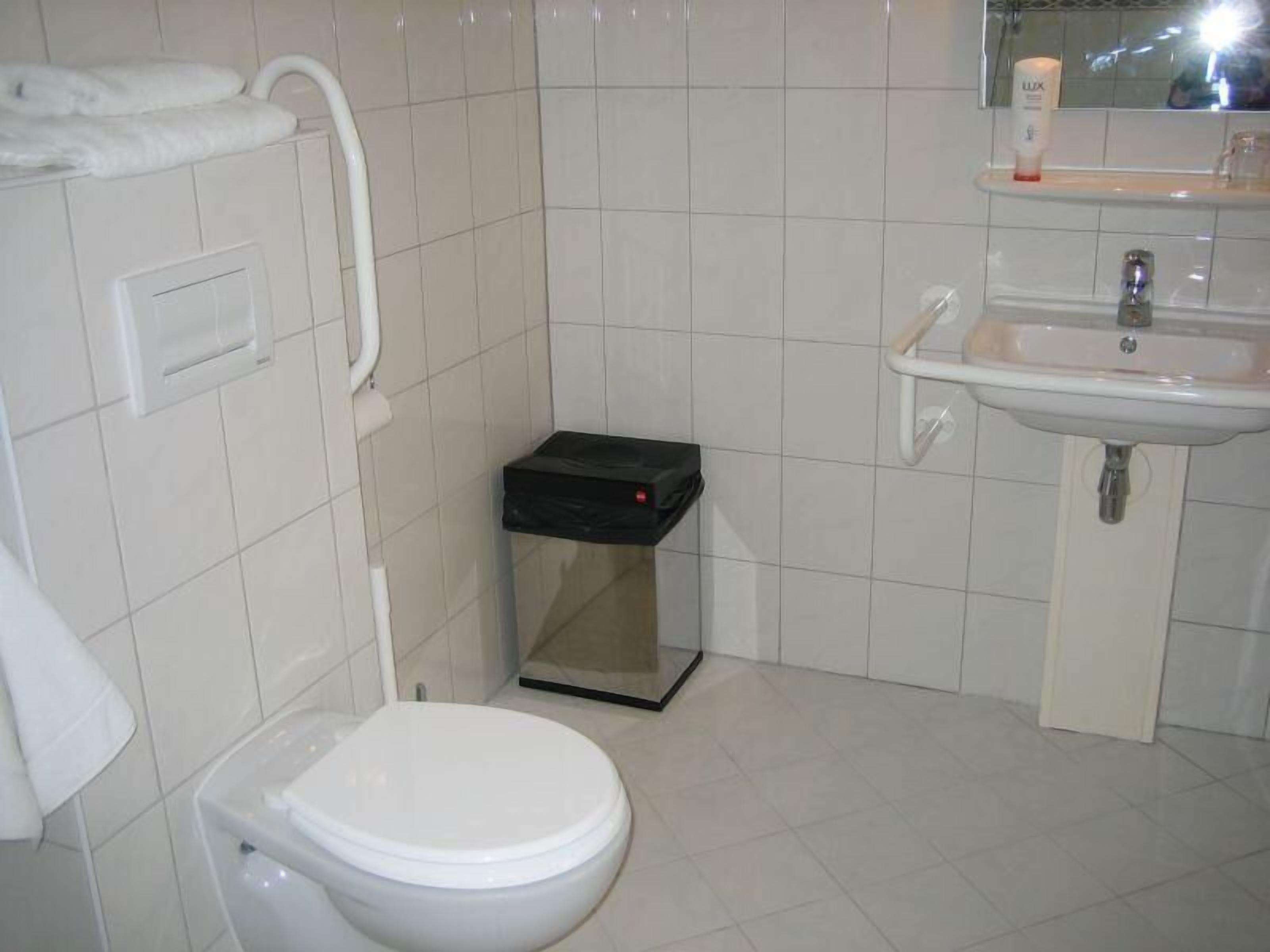 A small, clean bathroom with a toilet, a sink, and a trash bin.