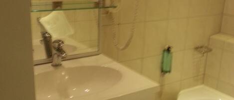 A bathroom with a white sink, a mirror, a hairdryer, and a bathtub.