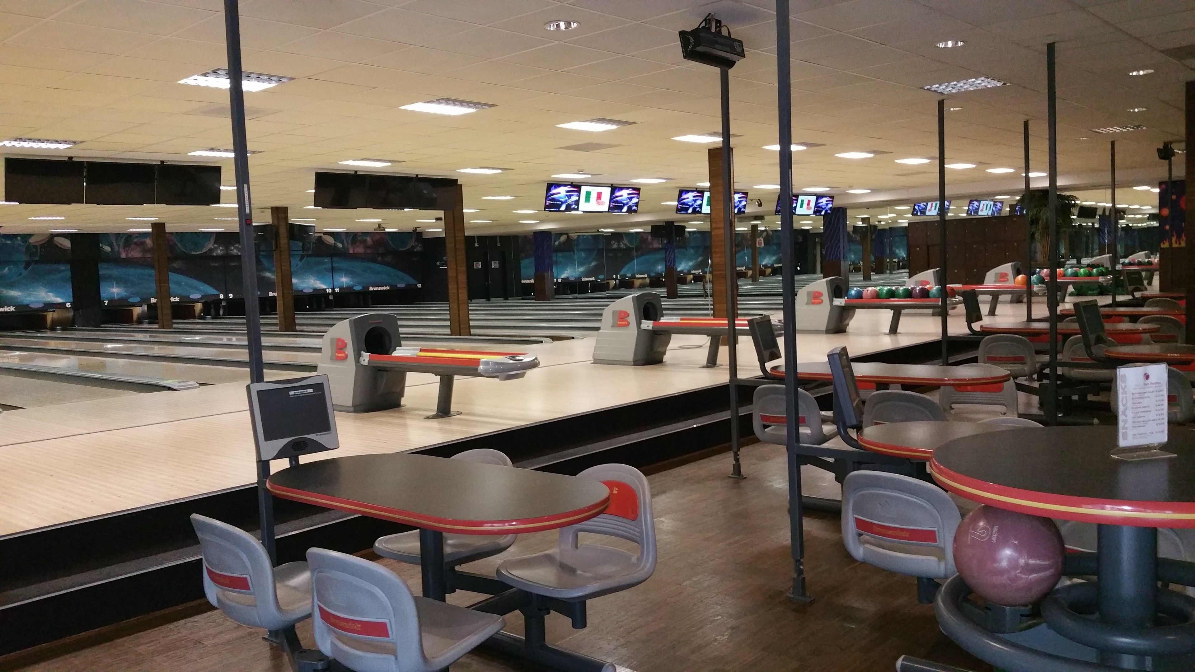 Un bowling doté de nombreuses pistes, d’espaces pour s’asseoir et d’écrans suspendus au plafond qui affichent les scores.