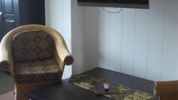 A living room with a dark coffee table, a patterned armchair, and a television mounted on the wall.