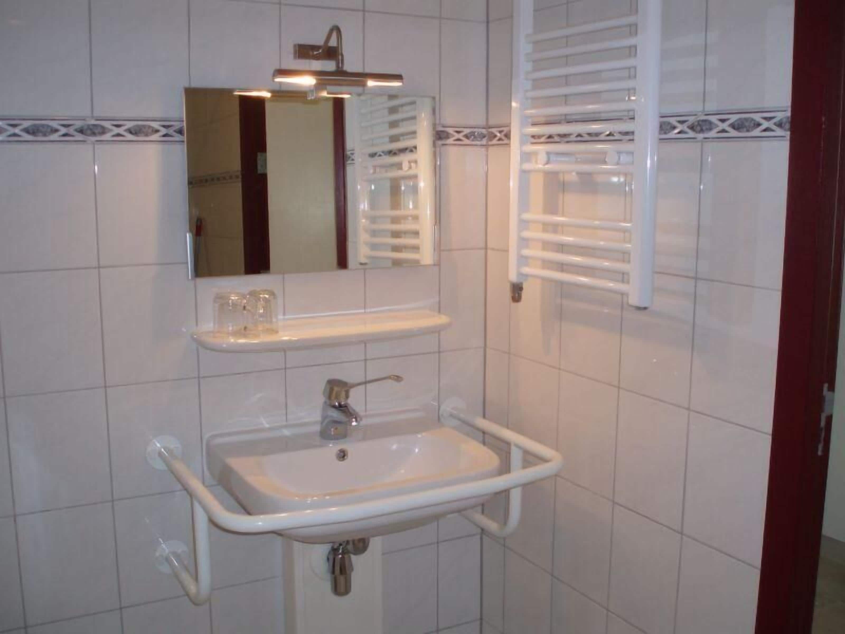 A bathroom with a white sink, mirror, and towel rack.
