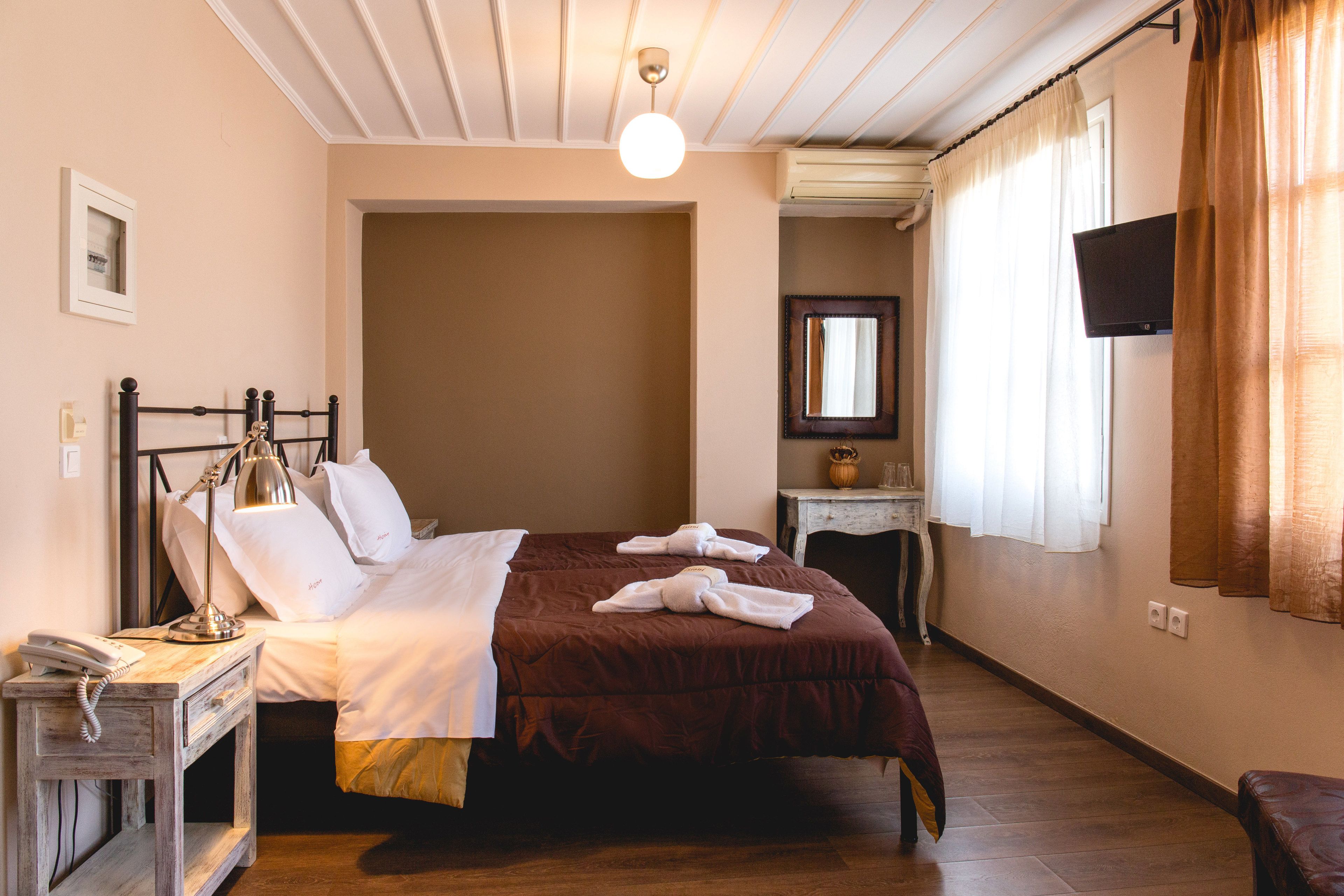Une chambre d’hôtel équipée d’un lit, d’une table de chevet, d’une lampe et d’un téléviseur à écran plat fixé au mur.