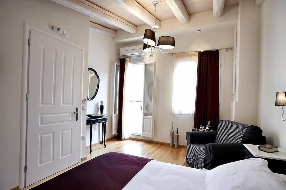 A hotel room with a bed, a desk, a chair, a mirror, and a window with curtains.