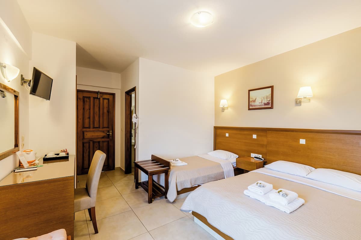 A hotel room with a bed, two bedside tables, a chair, a desk, a television, and a door.